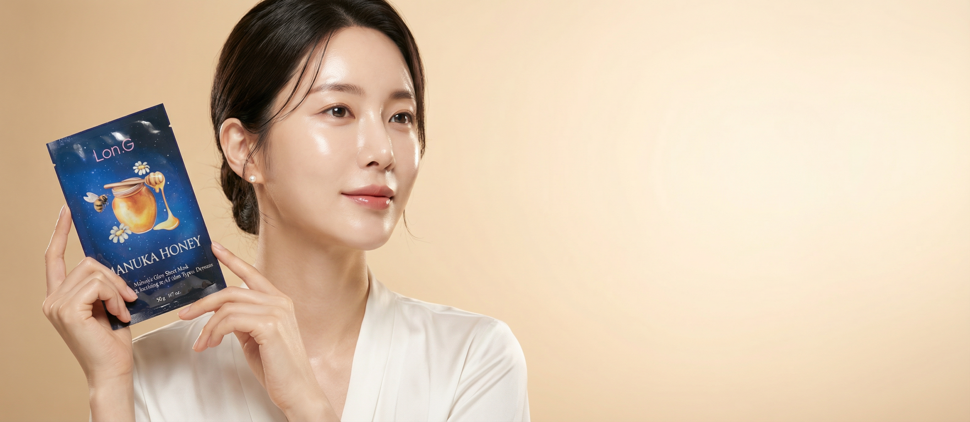 Vrouw met stralende huid houdt een Lon.G Manuka Honey gezichtsmasker sachet omhoog tegen een warme beige achtergrond. Het product heeft een donkerblauwe verpakking met een afbeelding van een honingpot en bij.